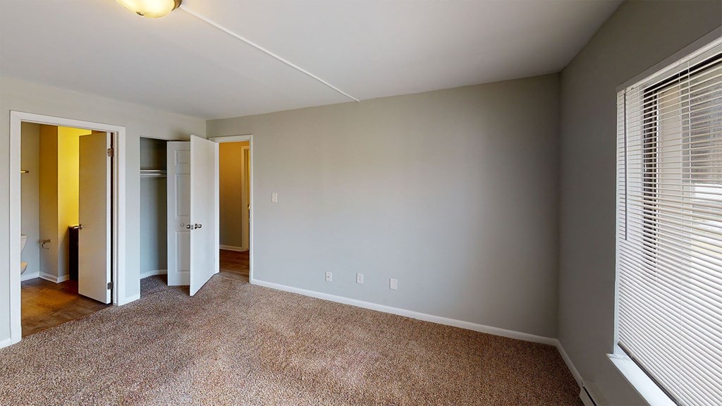 a bedroom with a large window and a carpeted floor
