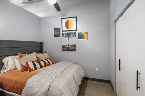 A bedroom with a bed, pillows, and pictures on the wall.