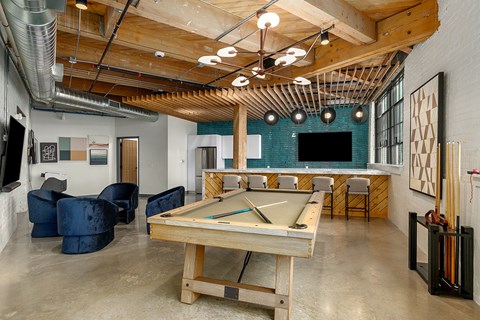 A room with a pool table and a bar area.