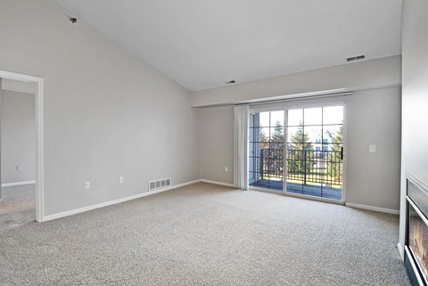 A sparsely furnished room with a sliding glass door.