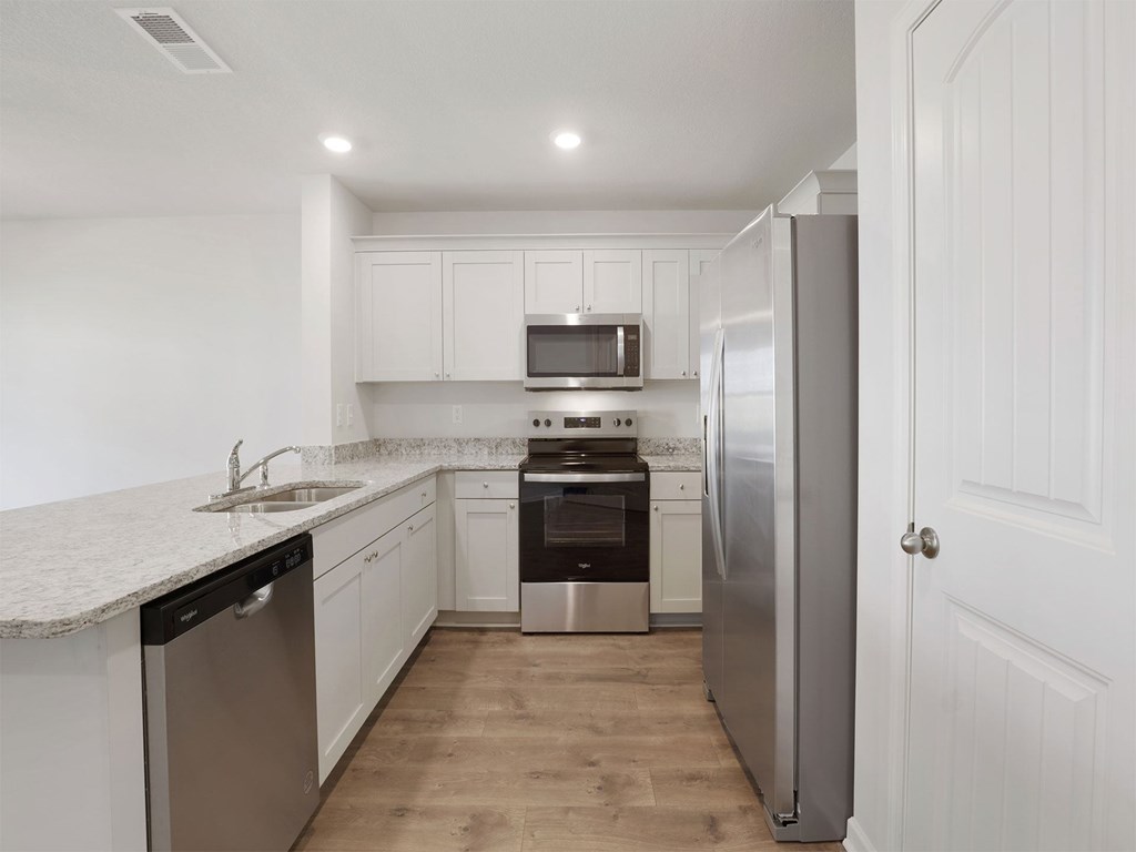 A kitchen with white cabinets and a stainless steel refrigerator.