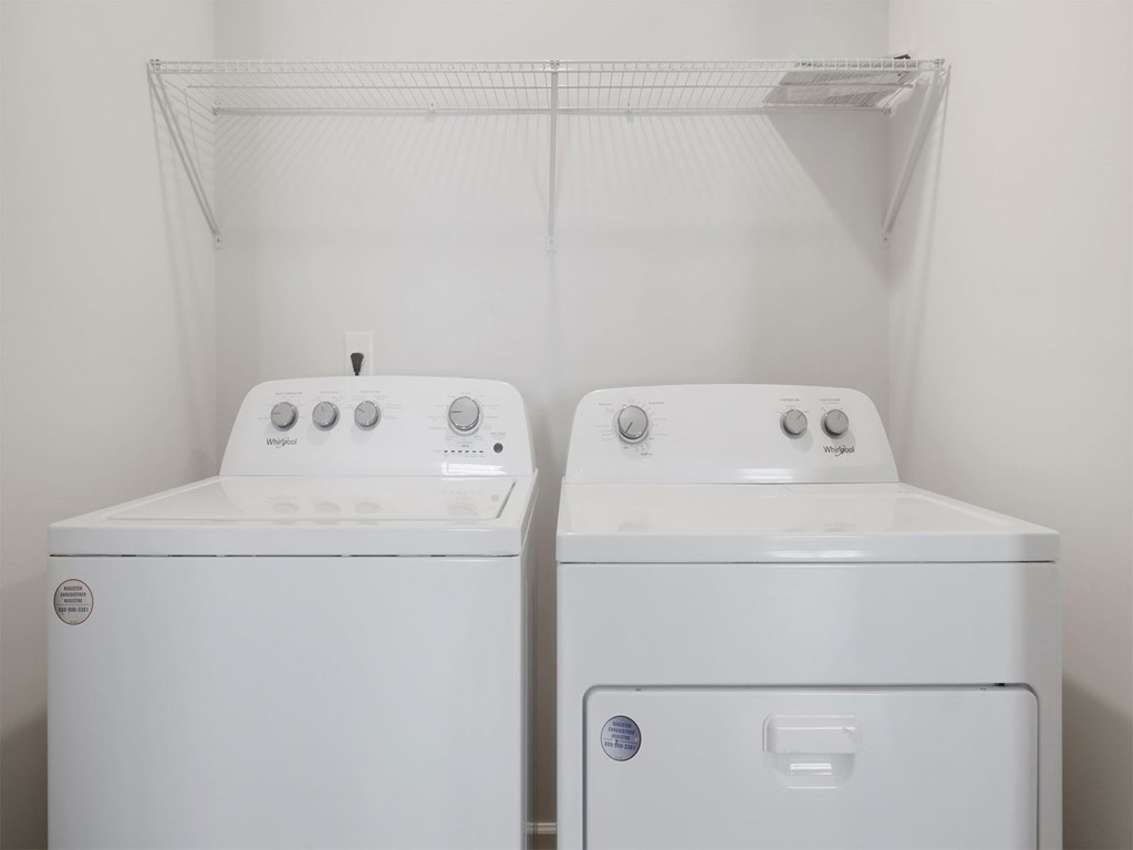 Two white washing machines in a small laundry room.