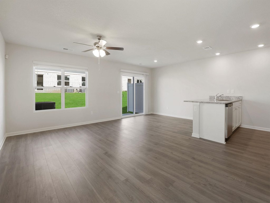 A spacious room with a ceiling fan and a kitchenette.