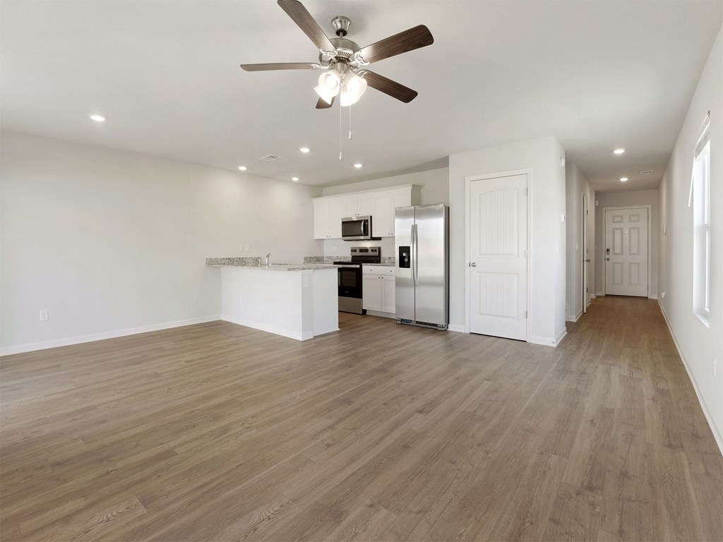 A spacious room with a ceiling fan and wooden flooring.