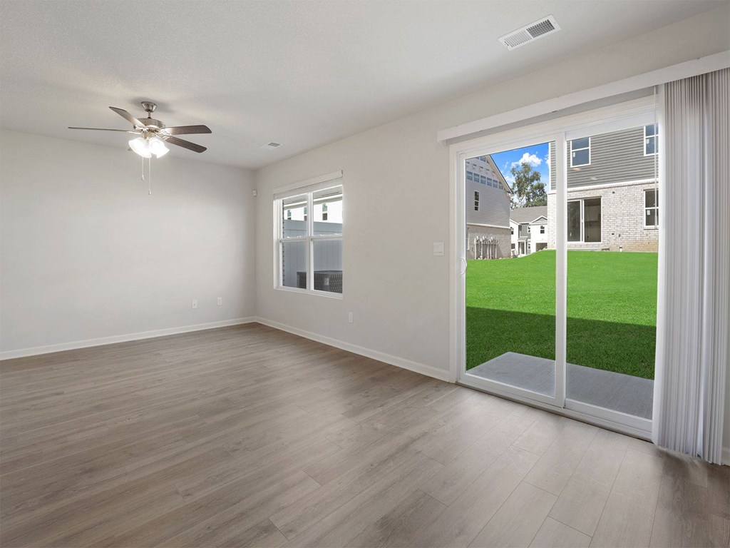 A room with a ceiling fan and sliding glass doors.