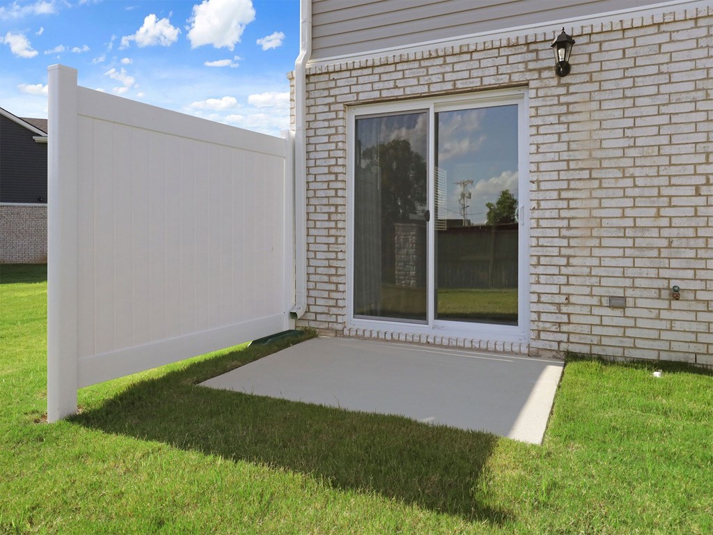 A white fence is in front of a brick house.