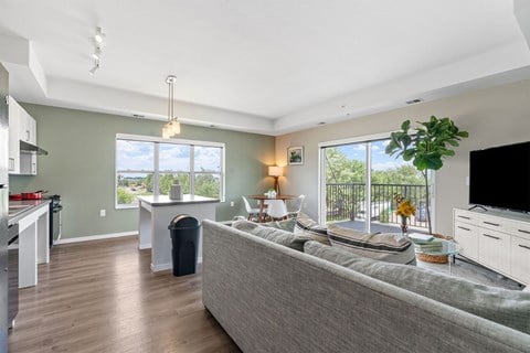 A living room with a grey couch and a television on the right side.