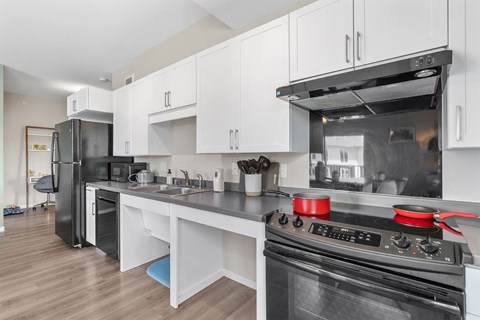 A modern kitchen with a black stove top oven and white cabinets.