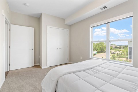 A bedroom with a large bed and a view of the outdoors through a sliding glass door.