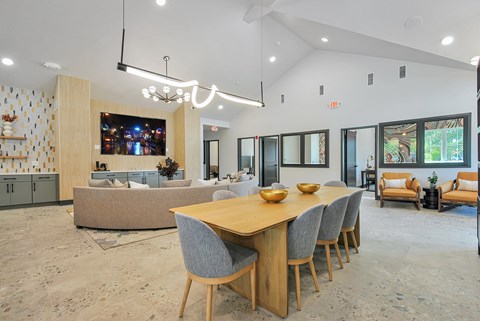 A modern dining room with a long wooden table and grey chairs.