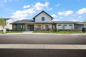 A modern house with a large front yard and a clear blue sky.
