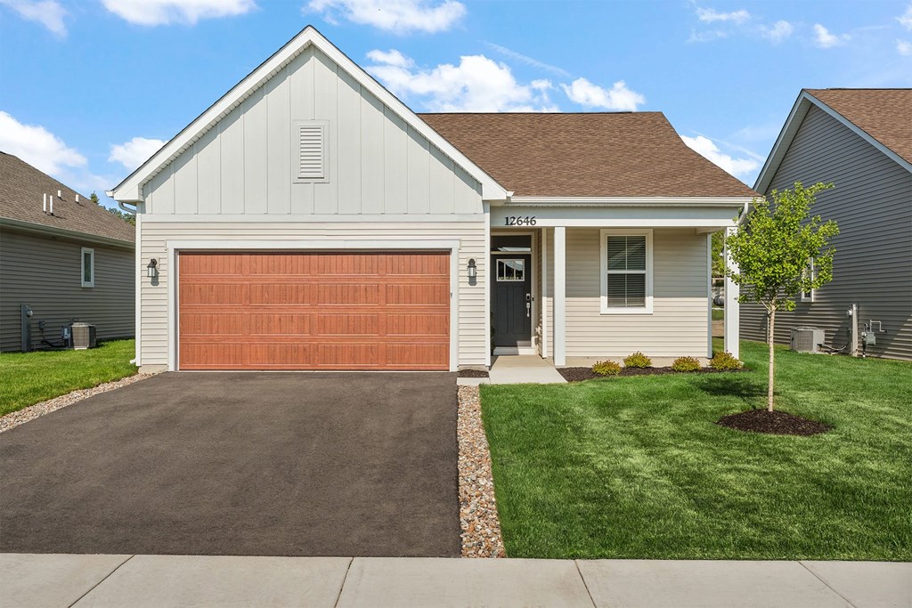A house with a brown garage door and a white house number.