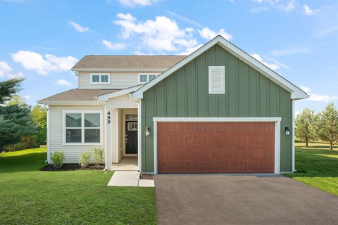 A house with a green garage door and a brown roof.