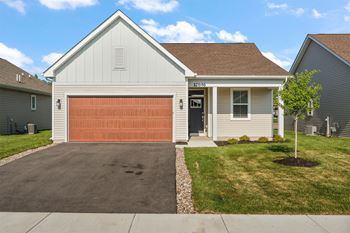 A house with a brown garage door and a white house number.