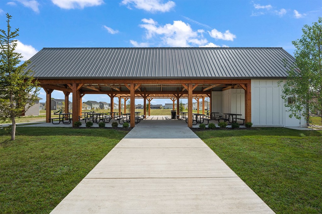 A pavement leads to a pavilion with a white building and a black roof.