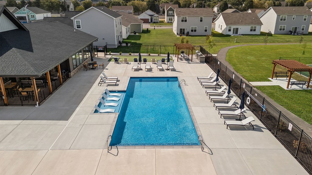 A large swimming pool surrounded by lounge chairs and a pavilion.