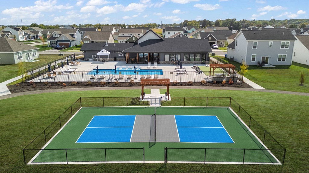 A tennis court is surrounded by a fence and a pool.