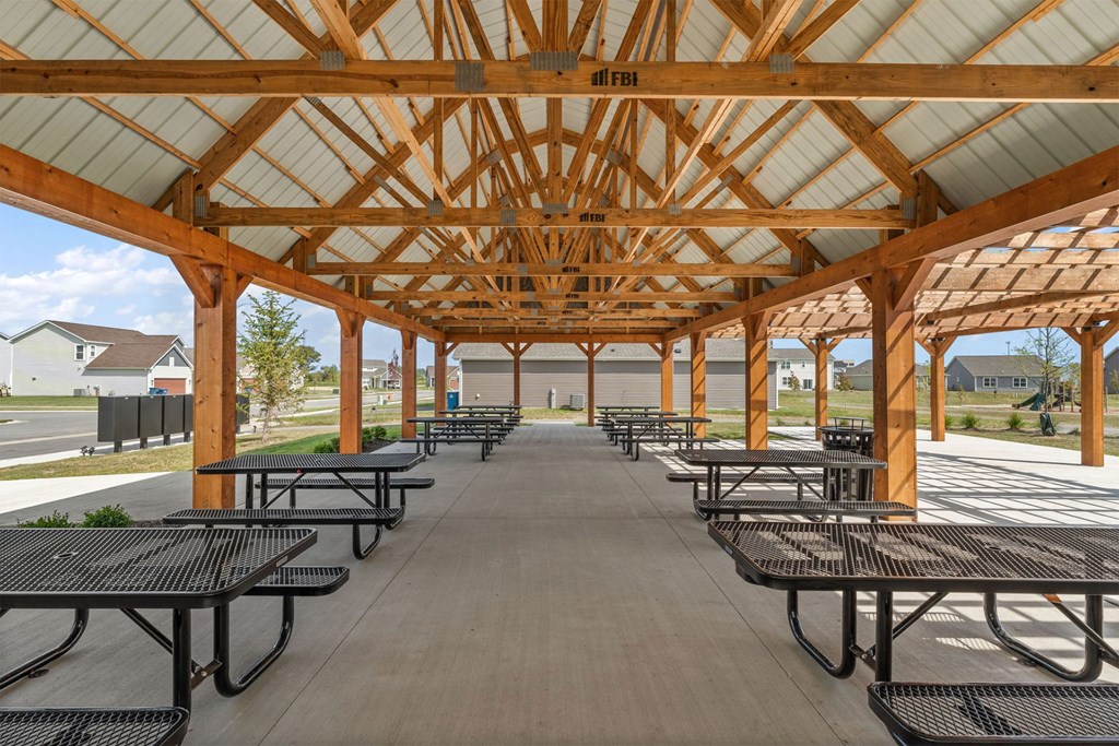 A wooden pavilion with black benches is shown.