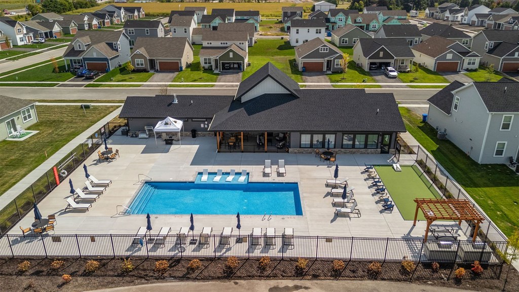 A swimming pool surrounded by lounge chairs and umbrellas in a residential area.