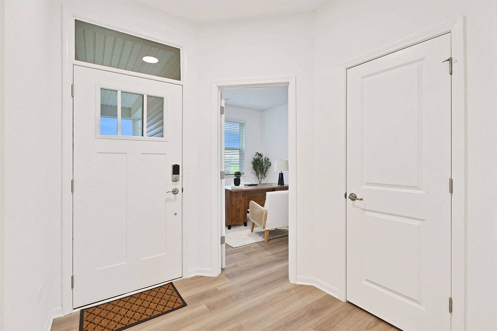 A white door with a glass window is open to a room with a desk and a chair.