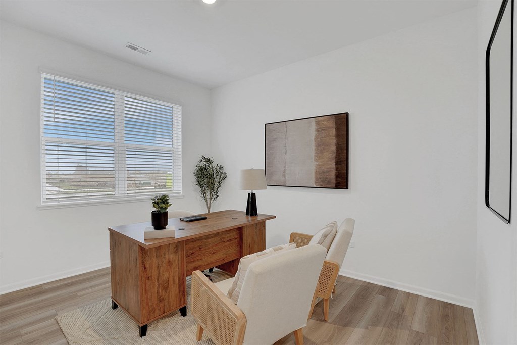 A room with a desk and chair in front of a window with blinds.