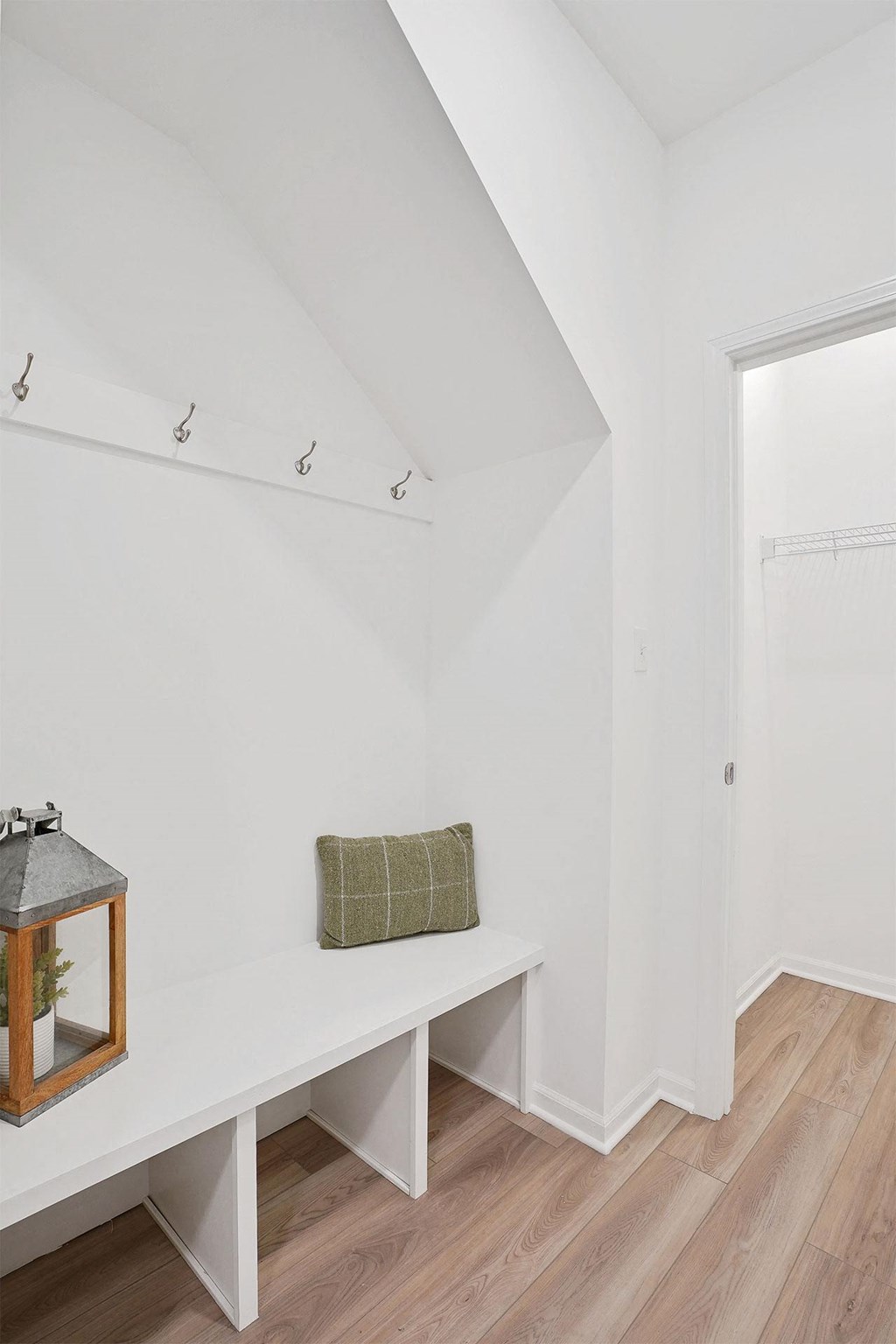 A white bench with a green pillow and a lantern on it.