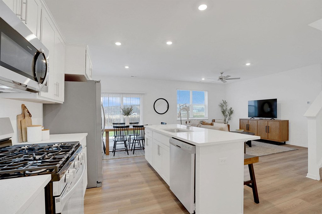 A modern kitchen with white cabinets and a black stove top.