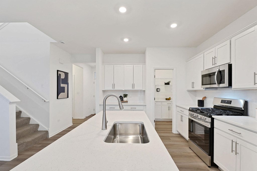 A modern kitchen with white cabinets and stainless steel appliances.