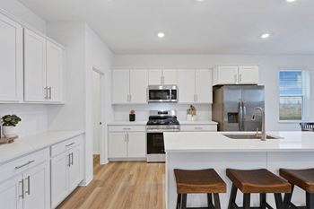 A kitchen with white cabinets and a wooden floor.