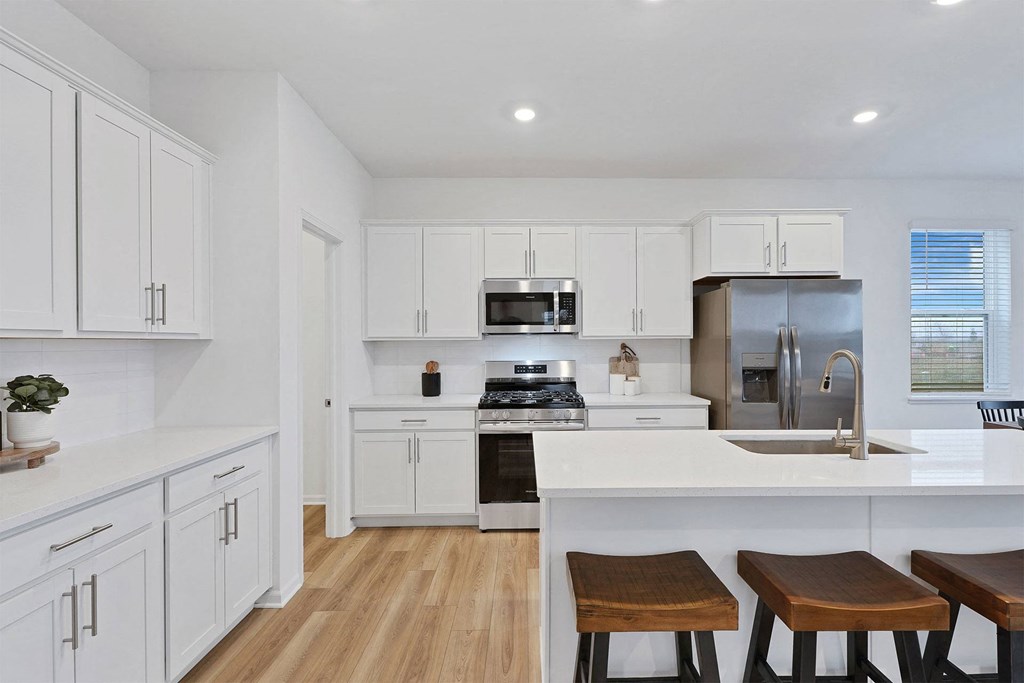 A kitchen with white cabinets and a wooden floor.