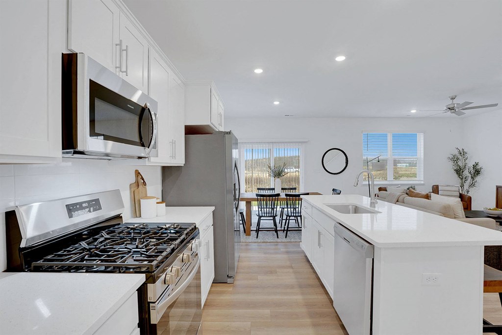 A modern kitchen with white cabinets and a black stove top.