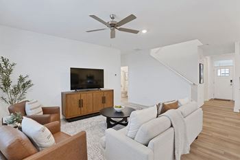 A living room with a brown leather chair, a white couch, and a wooden cabinet.