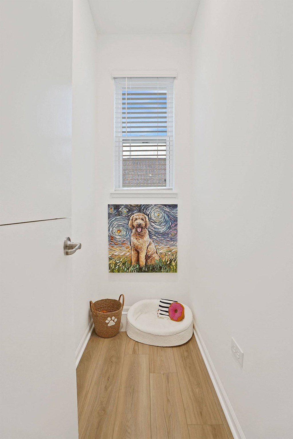 A dog painting hangs on the wall above a dog bed.