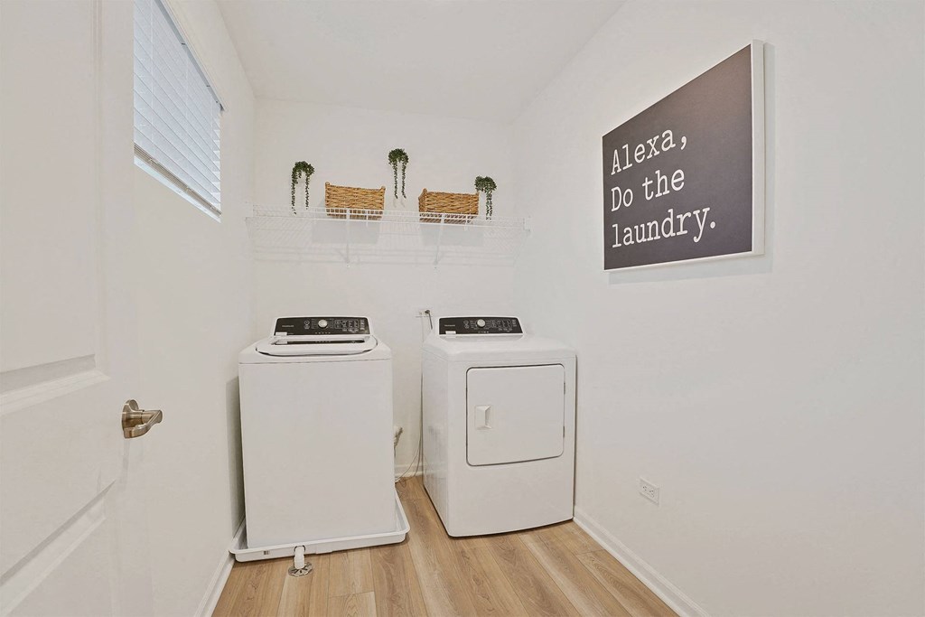 A laundry room with a sign that says "Alexa, do the laundry.".