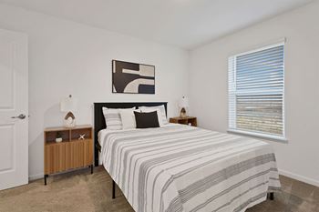 A bedroom with a bed, nightstand, and lamp.