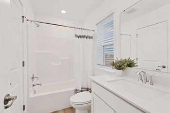 A white bathroom with a toilet, sink, and bathtub.