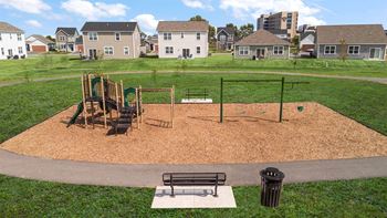 A playground with a slide, swings, and a seesaw.