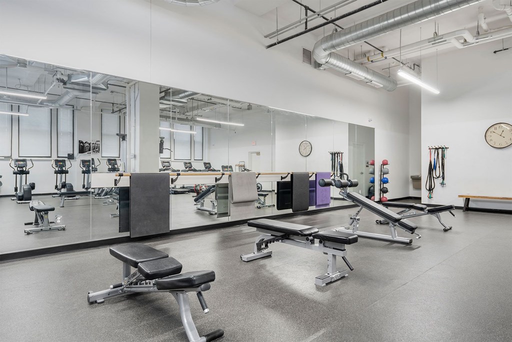 A gym with a variety of equipment including weights and benches.