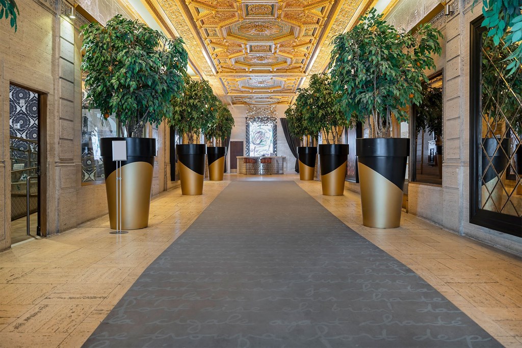 A long hallway with golden planters on each side.