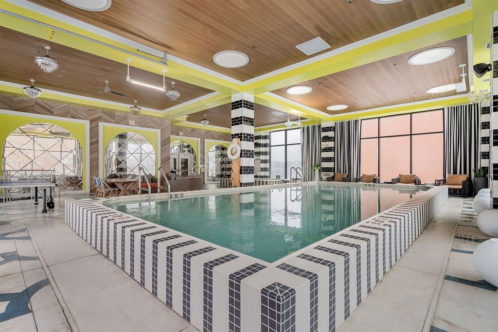 A large indoor swimming pool with a striped tile border.