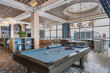 A pool table is in the middle of a room with a view of the city.