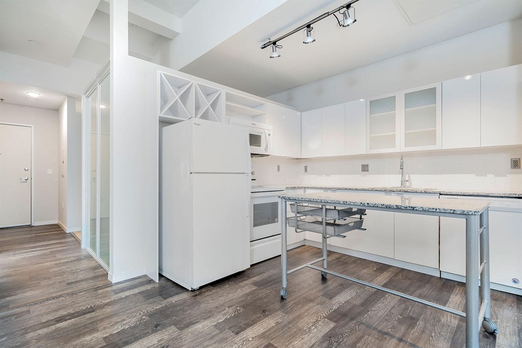 A kitchen with white cabinets and a wooden floor.