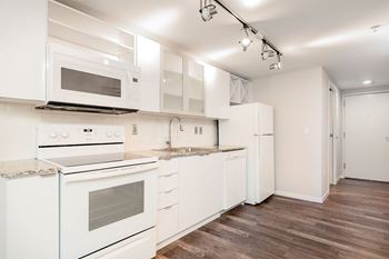 A kitchen with white appliances and wooden floors.
