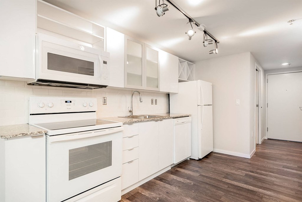 A kitchen with white appliances and wooden floors.