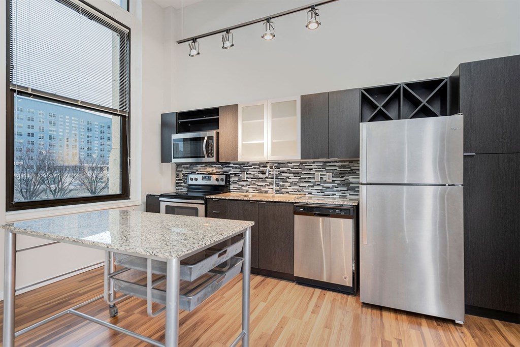 A modern kitchen with a granite countertop and stainless steel appliances.
