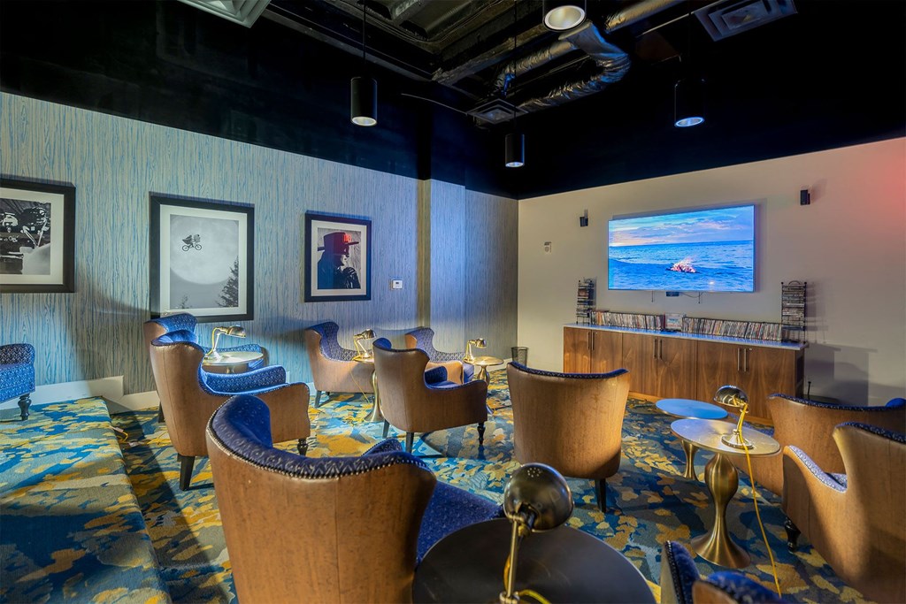 A room with blue chairs and a television on the wall.