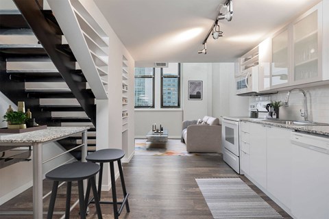 A modern kitchen with white cabinets and a wooden floor.