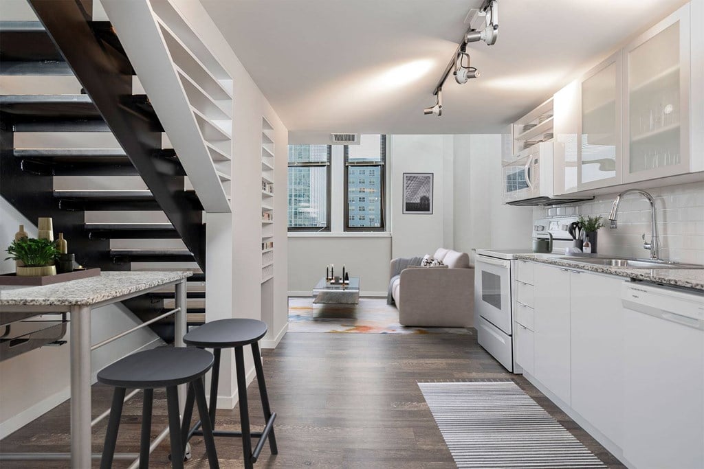 A modern kitchen with white cabinets and a wooden floor.