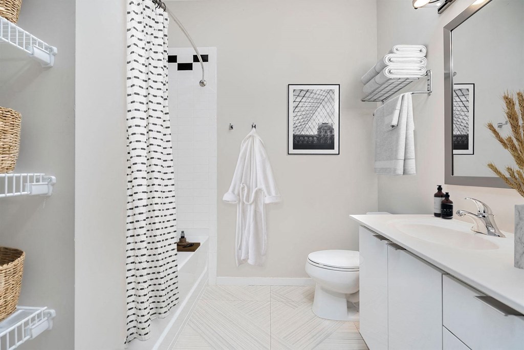 A white bathroom with a toilet, sink, and a shower curtain.