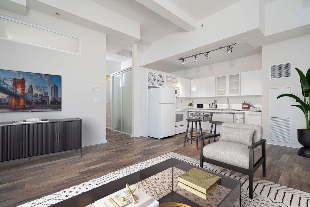 A modern living room with a large painting on the wall and a kitchen area in the background.
